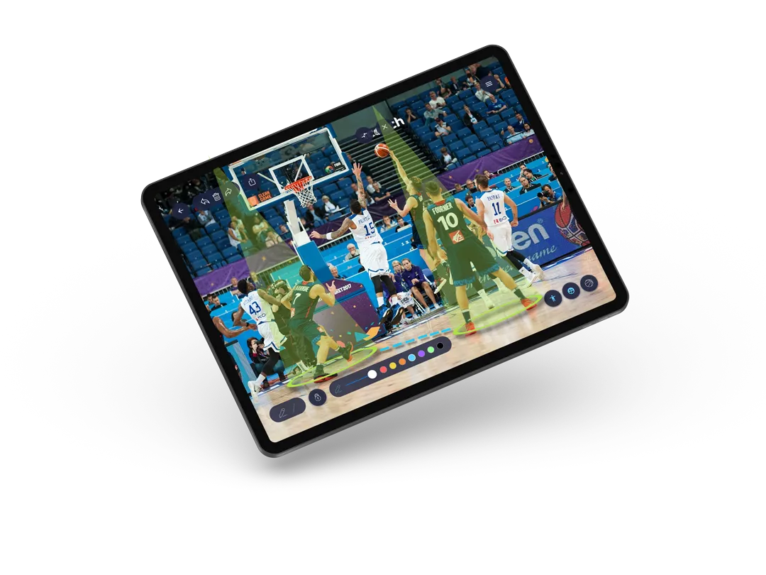Tablet con la pizarra táctica de Bcoach dibujando sobre una imagen de un partido de baloncesto